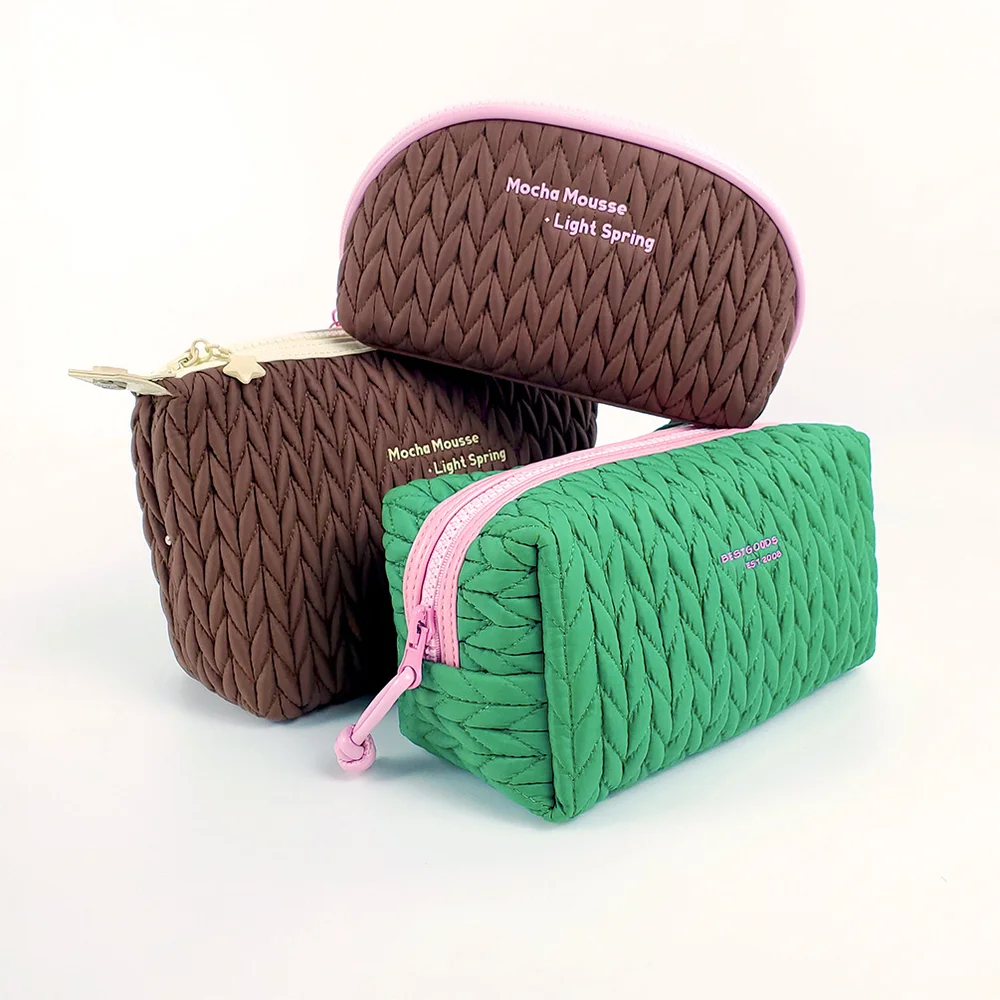 Three quilted puffer cosmetic bags in mocha brown and kelly green with pink zippers and gold star charm, arranged on white background