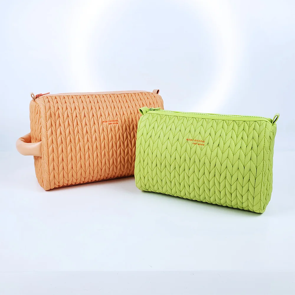 Peach and lime green chevron-braided quilted zippered cosmetic pouches, larger peach pouch with top handle, on light gray studio background