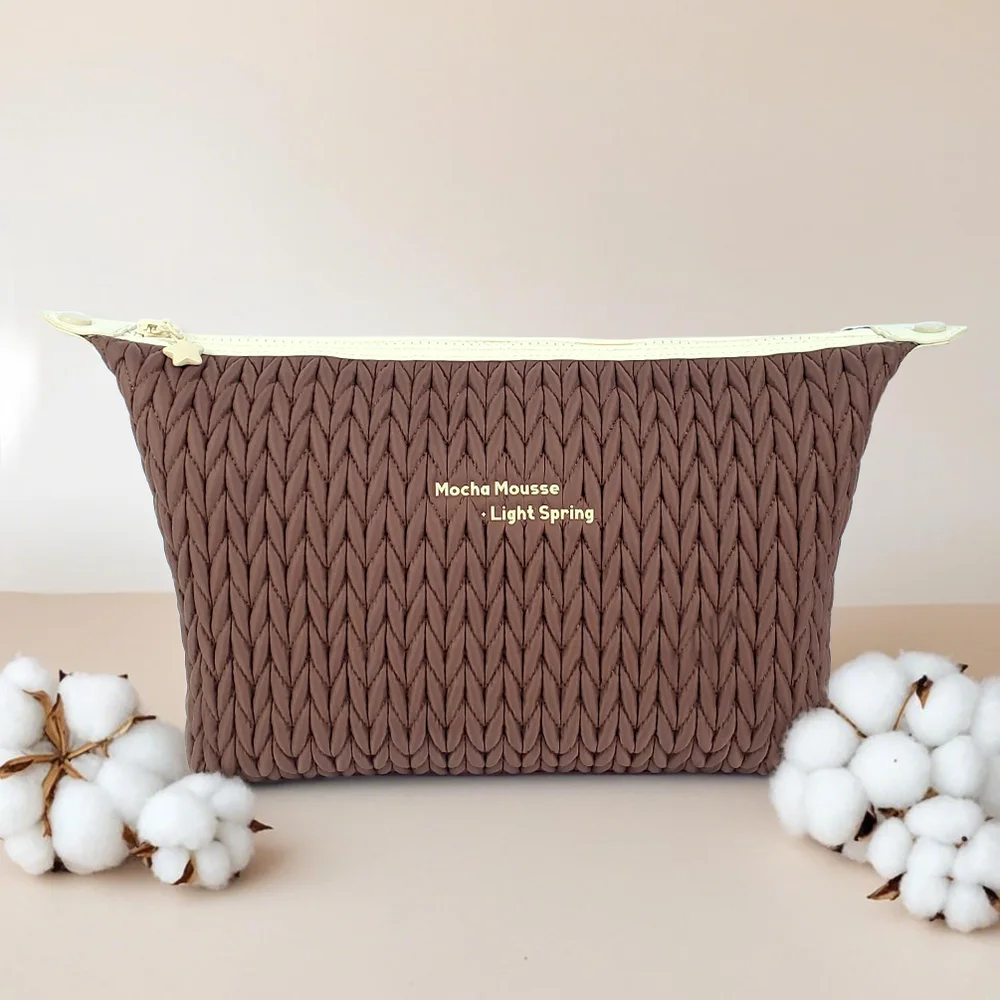 Mocha brown chevron-knit zip pouch with cream zipper, gold star pull, embroidered Mocha Mousse Light Spring, styled with cotton stems on beige backdrop