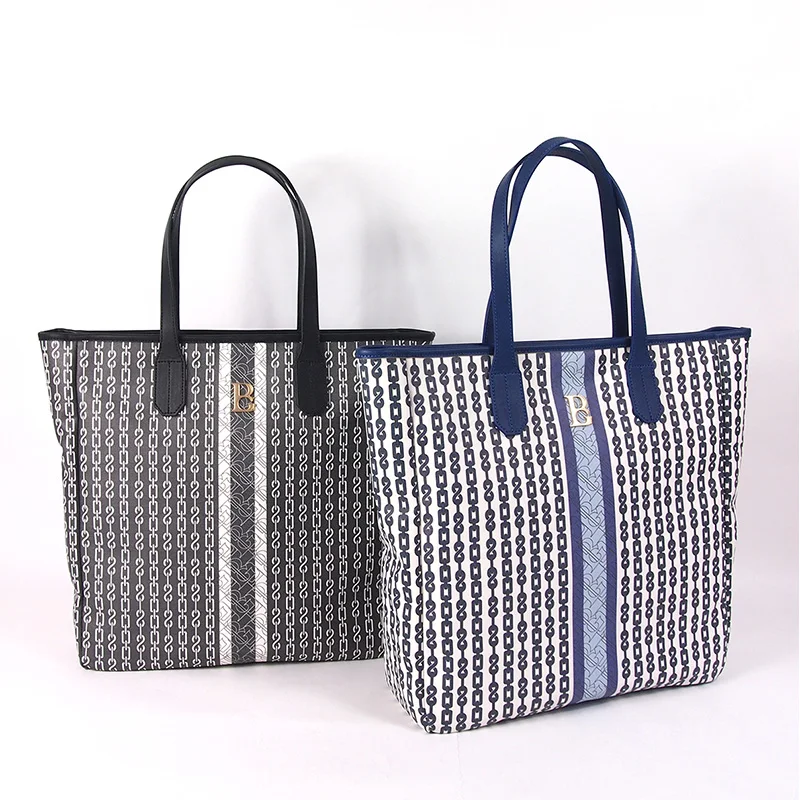 Two chain-link monogram print tote bags with smooth leather top handles and gold B logo, one navy and white, one charcoal and white, side by side on a white background