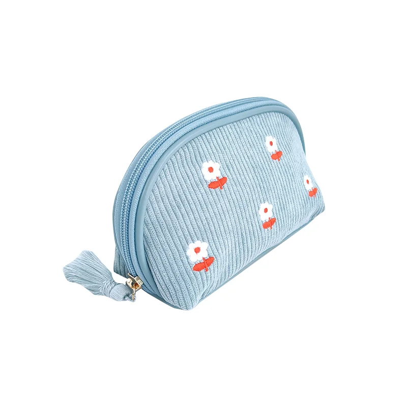 Light blue wide-wale corduroy dome pouch with white daisy embroidery, gold zipper and blue tassel on white background