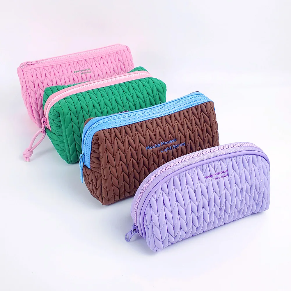Four quilted nylon zipper pouches in pink, green, brown, and lavender arranged in a row on a white background