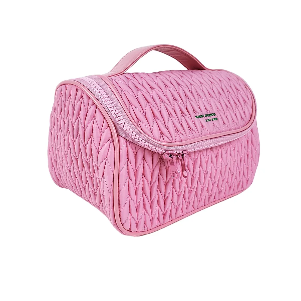 Rose-pink chevron-quilted puffer vanity case with top handle, curved zipper lid, and embroidered BEST GOODS logo on white background