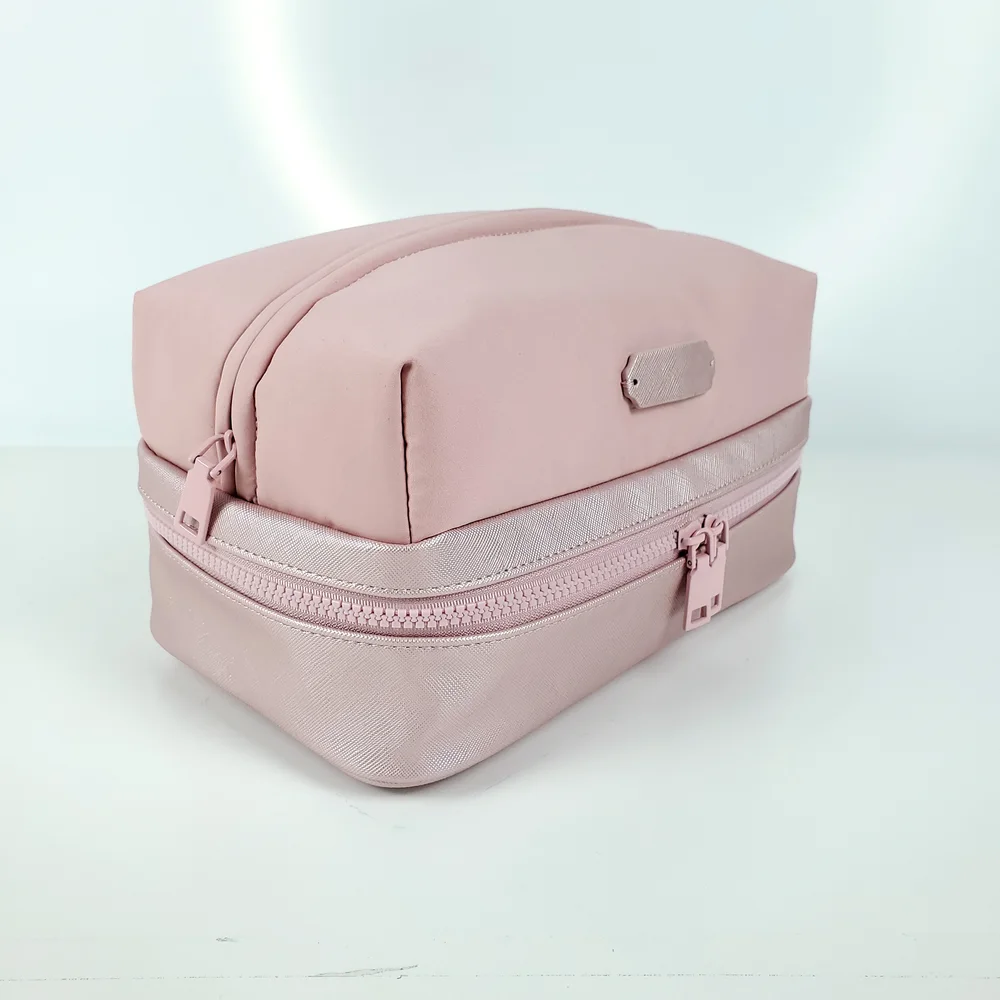 Blush-pink two-tier zip vanity case with matte nylon top and saffiano PU base on white background